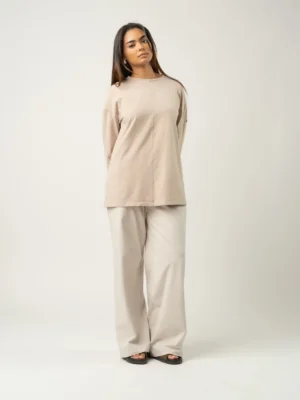 T-shirt oversize couleur latte porté avec un pantalon clair, style minimaliste