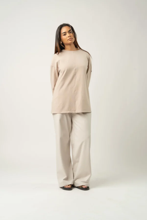 T-shirt oversize couleur latte porté avec un pantalon clair, style minimaliste
